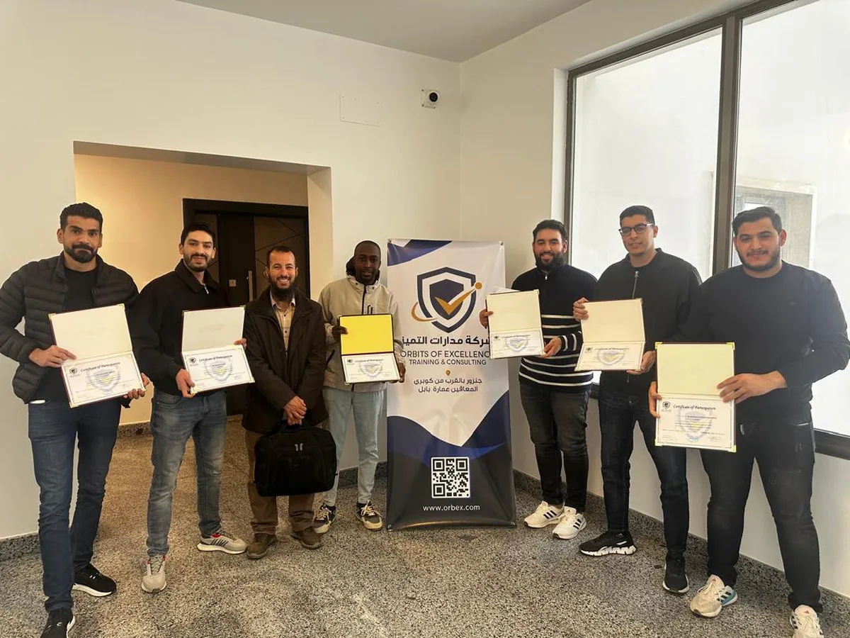 Participants holding certificates beside the Orbits of Excellence banner